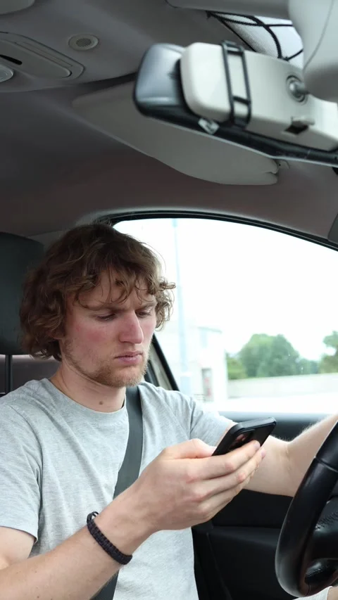 Distracted driver stares at a smartphone while moving through city traffic Stock Footage 342924289