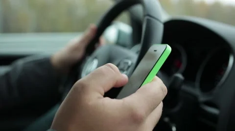 Distracted driver using phone to text while driving. Close-up of hand with phone Stock Footage