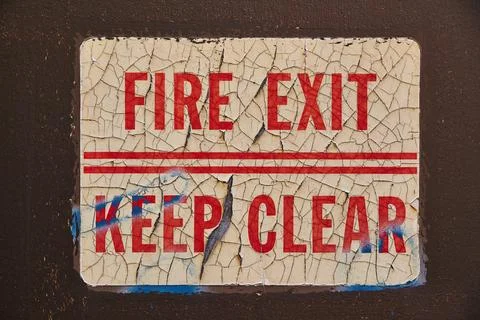 Distressed Fire Exit Sign on Dark Wall - Vintage Safety Neglect Stock Photos