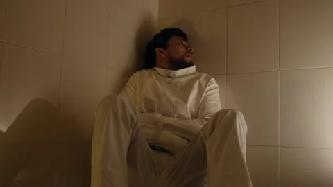 Distressed Man in Cell Wearing White Straitjacket Looking Anxious Stock Footage 324959646