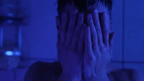 A distressed young man in the shower, hitting his head as he struggles with Stock-Footage 306220328
