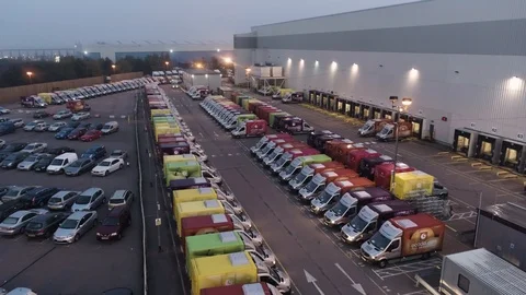Distribution warehouse, bright coloured vans waiting outside, drone aerial 4K Stock Footage 101168277