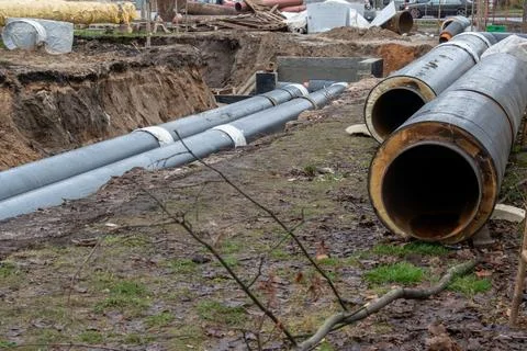 District heating pipeline installation in open trench on construction site Stock Photos