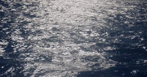 Disturbed storm blue ocean water surface with sun reflections at sunrise, slo Stock Footage 325606308