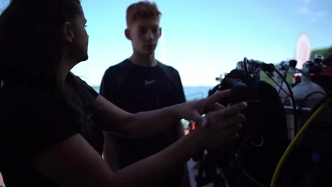 Dive instructor demonstrating regulator function directly to student beside 스톡 동영상 331565974
