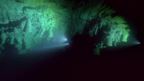 Dive light reveals textured rock walls inside a dark cenote Stock Footage 341395024