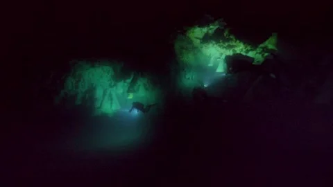 Dive light scans a submerged formation in dark cenote water Stock Footage 341394815