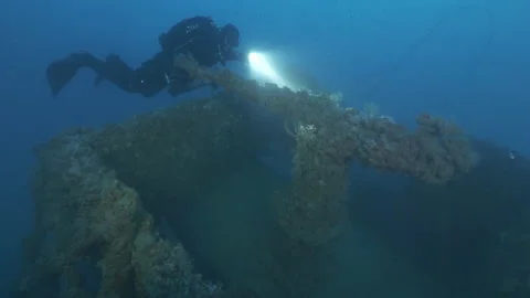 Diver approaches the machine gun of the wreck Adernò swims next and leaves Stock Footage 227368927