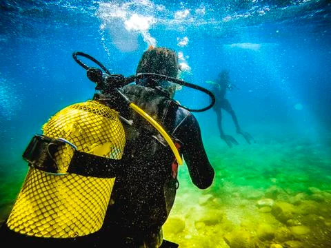 Diver back to camera, looking to another diver in the sea. Stock Photos