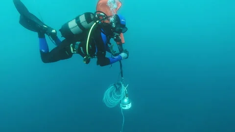 Diver carrying an underwater seismometer Stock Footage 263115403