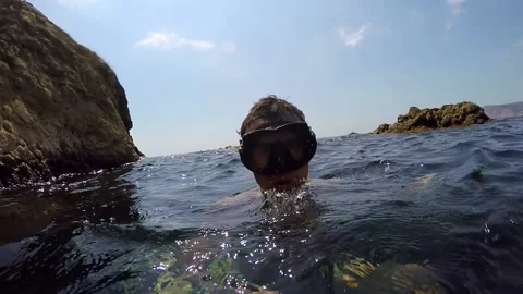 Diver dives into the water swims between the rocks and floats up and beats in Stock Footage 88463077