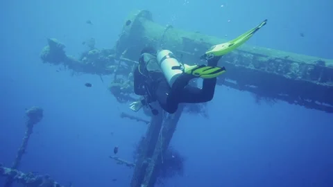 Diver exploring shipwreck in the distance Stock Footage 241086477