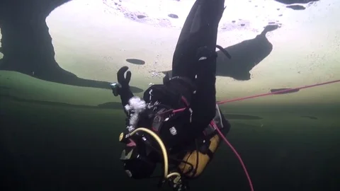Diver goes head down underwter in ice of White Sea. Video stock 73668889