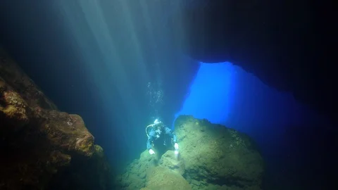 Diver inside the cave with sun rays 스톡 동영상 127940710