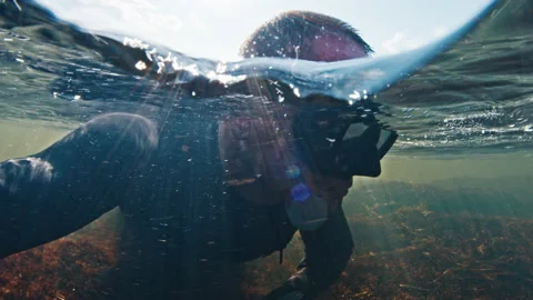 Diver with mask swims in the shallow rapid river and watches around 動画素材 204862503