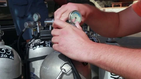 A diver putting a regulator on a dive tank and opens it. Equipment Stock Footage 82731584