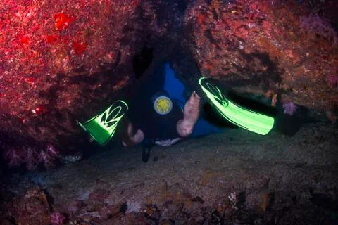 Diver squezing through a cave exit under water Stock Photos