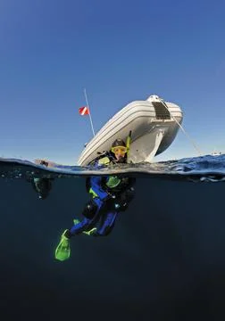 Diver on surface by boat split level Foto stock
