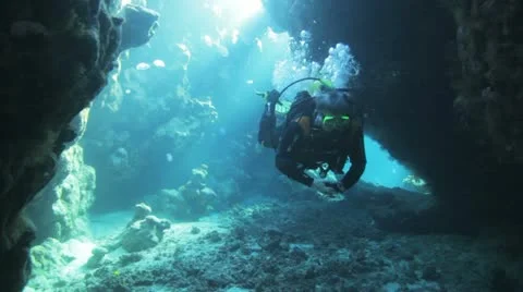 Diver swimming inside the cave under the natural sun light Stock Footage 22640961