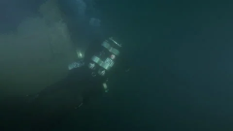 Diver swims around the bow of the shipwreck Adernò and illuminates it Stock Footage 228075502
