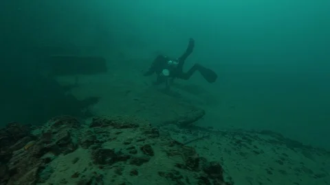Diver swims on the remains for the dam construction, San Domenico lake, Italy Stock Footage 108689934