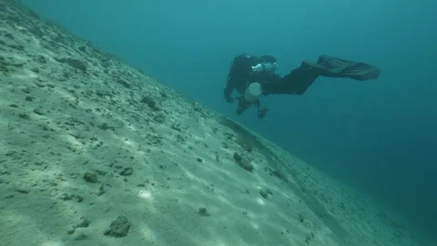 Diver swims on the sandy bottom with rocks of the lake, San Domenico lake, Italy Stock Footage 108696706