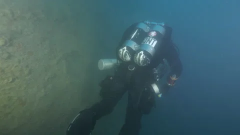 Diver with torch swims along the hull of the wreck Adernò illuminating it Stock Footage 227386389