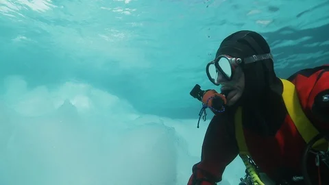 Diver touching a crystalline piece of ice in the Arctic Ocean Video stock 100635696