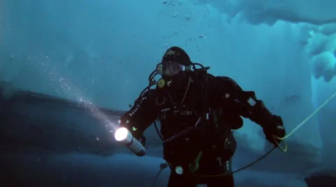 Diver under Arctic ice at the North Pole light the way a flashlight. Stock-Footage 62999694
