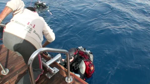 Diver in water about to step out of water onto boat and his friends help him. Video stock 233491871