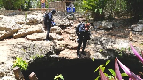 Divers fully equipped in a wetsuit in a mask and fins jump into a hole in the Stock Footage 90548645