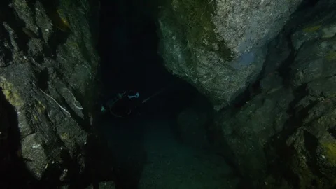 Divers illuminate the sandy bottom in the crack between rocks, Ustica, Med sea Stock Footage 126981753