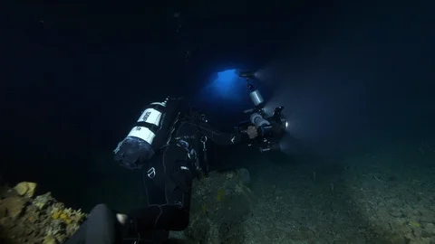 Divers pass through crack under the rocks at the seabed,Ustica,Mediterranean sea Stock Footage 126926516