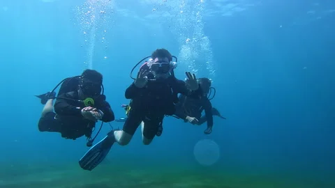 Divers with rising bubbles show OK gesture in clear ocean water Stock Footage 307491793