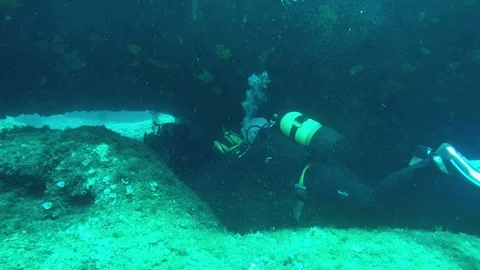 Divers swim through a cave Stock Footage 119132347