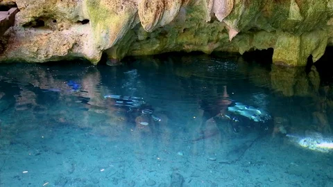 Divers swim under the water in the blue lake cave Dream Gate Cenote near Dos Stock Footage 90548683