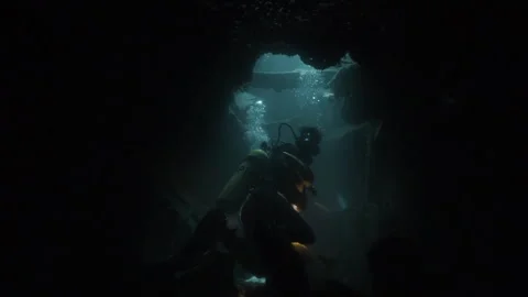 Divers swiming through a shipwreck Stockbeeldmateriaal 251838704