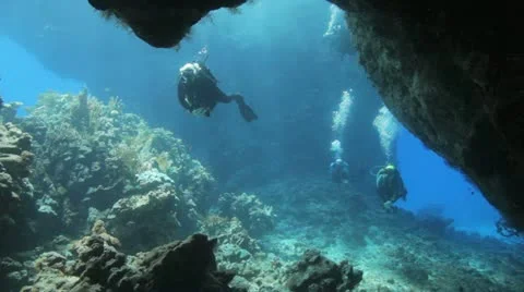 Divers swimming toward the cave Stock Footage 22643208