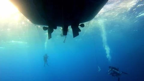 Divers swimming under the ship at the bottom of the Red sea in Egypt Stock Footage 234981132