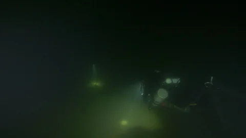 Divers with torch illuminate bottom of the lake, Trevignano lake, Italy Stock Footage 104447169