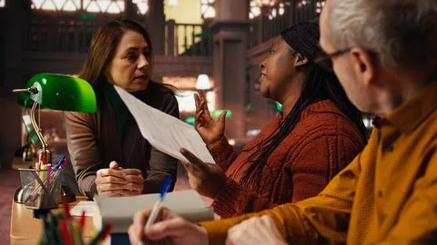 Diverse actors practicing theatre script with deep dedication in a library Stock Photos