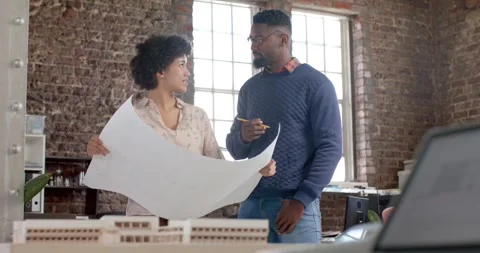 Diverse architect colleagues discussing work with building model and blueprints Stock Footage 344324602