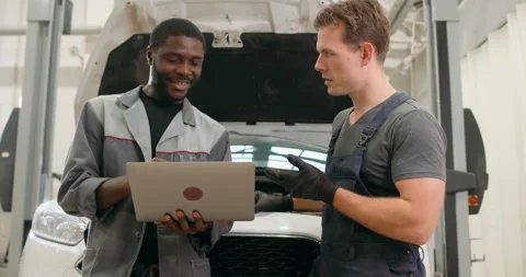 Diverse auto electicians checking up on car engines parts for fixing and repair Stock Footage 259610267
