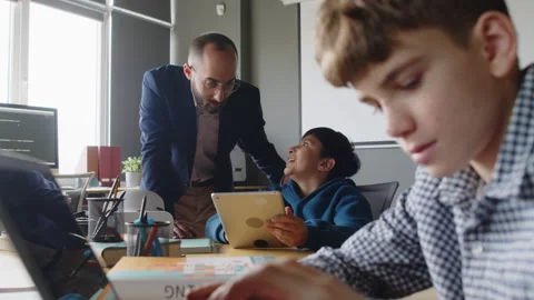 Diverse Boys Working on Coding Projects in Classroom and Teacher Checking Video stock 278126773