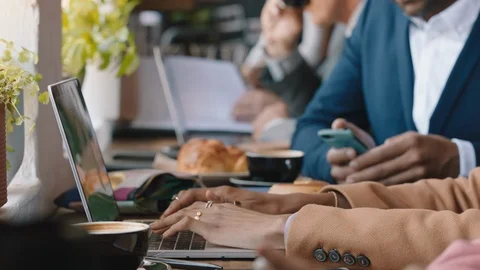 Diverse business people hands using laptop computers in busy cafe bustling with Stock Footage