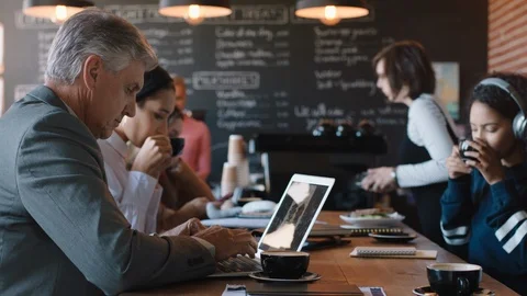 Diverse business people working in cafe bustling with activity drinking coffee Stock Footage