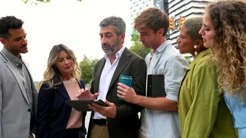 Diverse business team discussing project outdoors with tablet Stock Footage 326029828