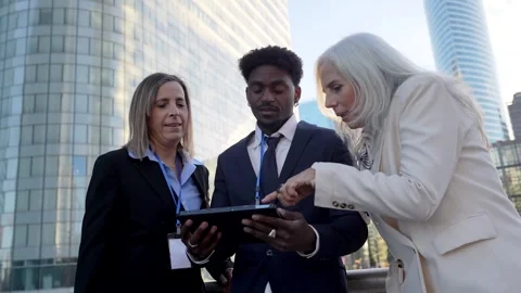 Diverse business team discussing project on tablet in financial district Stock Footage 326415780
