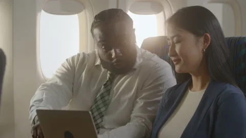 Diverse business team going over presentation on airplane, happy Stock Footage 233098735