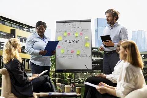Diverse business team hosting presentation with ideas roadmap on whiteboard Stock Photos